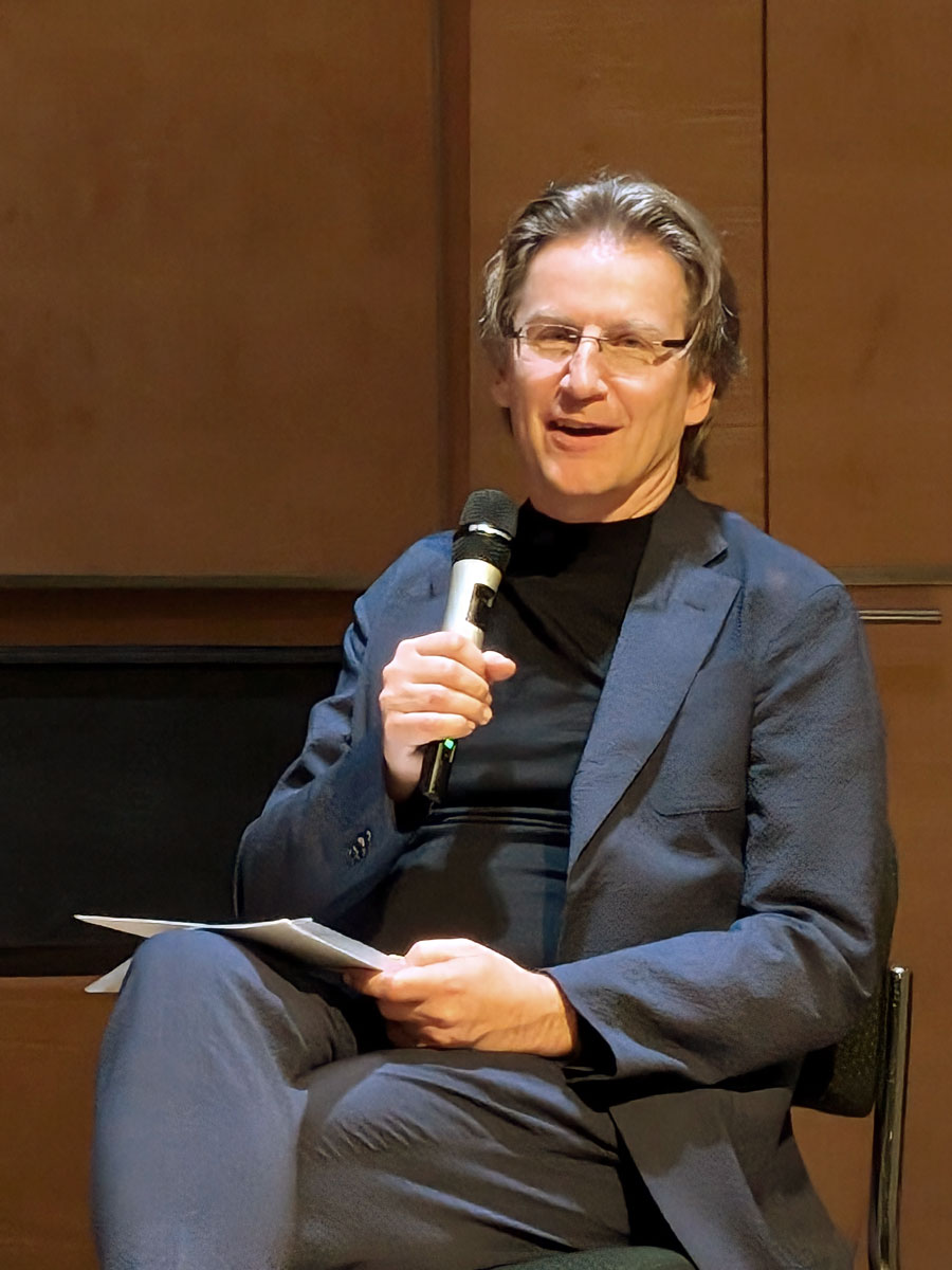 Prof. Dr. Dirk Mürbe mit Mikrofon in der Hand auf der Bühne in der Dresdner Musikhochschule