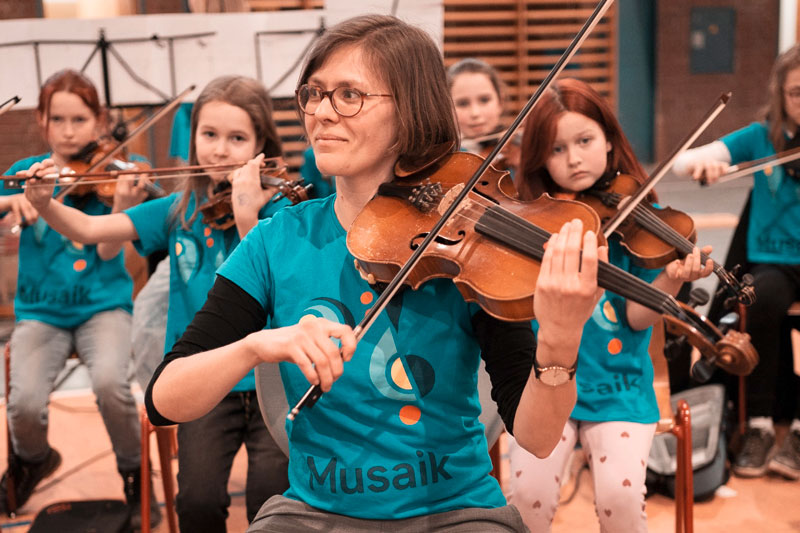 Die Musikerin Luise Börner, Violine spielend mit Musaik-Kindern im Hintergrund